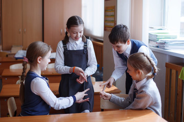 Pupils at the desk think and decide the task in the school. Primary education, training and people concept