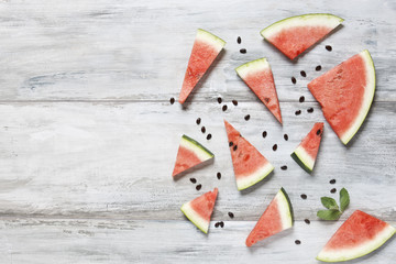Watermelon pattern. Sliced watermelon, seeds and mint on gray concrete  background. Flat lay, top view, close up.