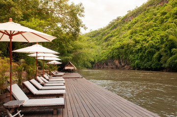 Resort style beach daybeds and umbrellas by river Kwai, Kanchanaburi, Thailand