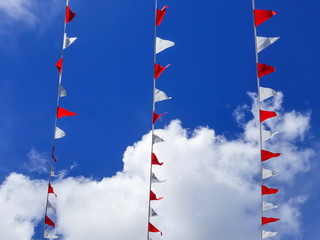 Garland of red and white triangle flags on blue sky background.