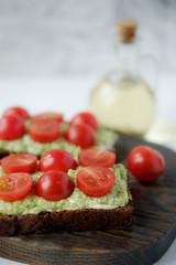 Pieces of toasted bread with cottage cheese, avocado and cherry tomatoes