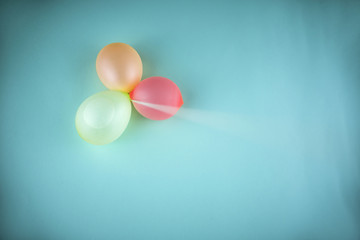 Globos de colores llenos de agua sobre un fondo azul unidos por una cuerda tensa desenfocada