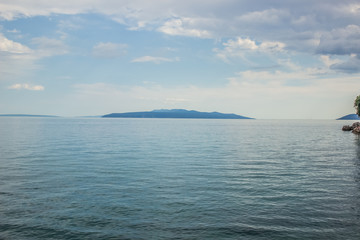 Obraz premium nature scenery landscape of waterfront resort stone empty coast district with sea water surface small waves horizon lane and one island on background in summer colorful day time
