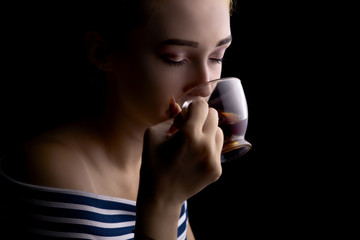 portrait of a beautiful girl drinking tea on a black background