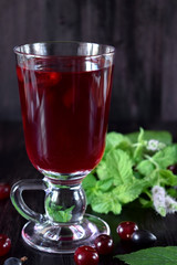 Berry kissel in a glass mug. Cherries and gooseberries are scattered around