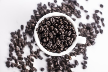 Brown coffee beans in white cup isolated on white background.