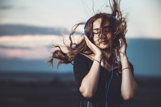 portrait of a beautiful girl in headphones listening to music on nature