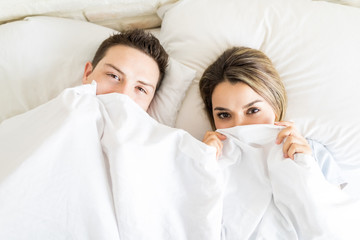 Boyfriend And Girlfriend Hiding Under Blanket While Lying In Bed