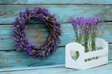 Lavender wreath and decorative box with heart & bouquets lavender in glass bottles on vintage blue background in the style of Provence.