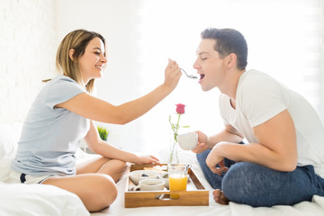 Obraz na płótnie Canvas Loving Girlfriend Feeding Man With Breakfast On Bed