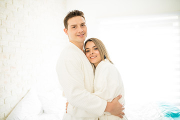 Couple Wearing Bathrobes While Hugging In Bedroom