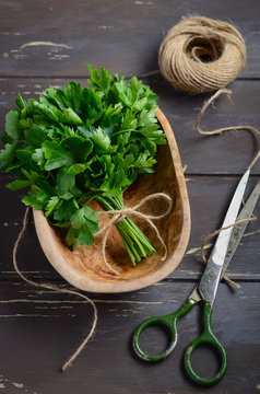 Fresh organic parsley bunch in a wooden bowl on the old rustic wooden table.