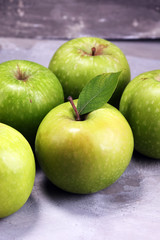 Ripe red apples with leaves on wooden background.