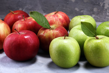 Ripe red apples with leaves on wooden background.
