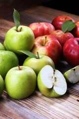 Ripe red apples with leaves on wooden background.