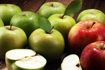 Ripe red apples with leaves on wooden background.