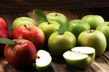 Ripe red apples with leaves on wooden background.