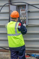 The electrician at the construction site connects the electrical panel
