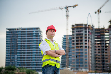Proud architect on a construction site in front of buildings and cranes