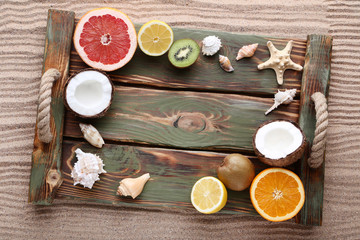 Seashells and starfishes with fruits on wooden tray