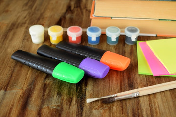 Paints, highlighters, brushes and stickers on a wooden table