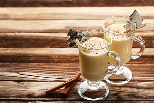 Eggnog in glasses with cinnamon on wooden table