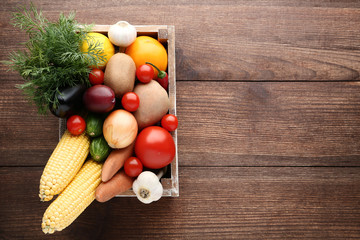 Ripe fruits and vegetables in crate on wooden table