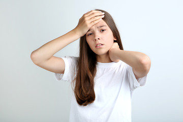 Fototapeta premium Young girl having headache on grey background