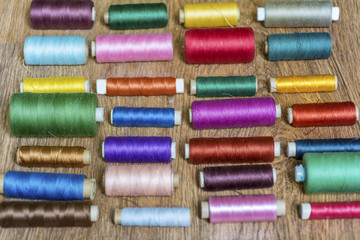 Multi Colored Thread Yarns and Vintage Scissors on Wooden Background 