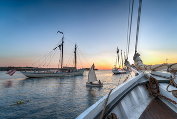 Sailboat Dingy Sails Between Wooden Boats at Sunset