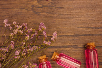 Flat lay organic essential oil and flower with copy space on brown wooden background