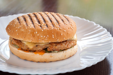 Juicy cheeseburger with cheese on a white plate
