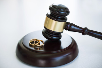 Close up of Judge gavel deciding on marriage divorce and two golden marriage ring