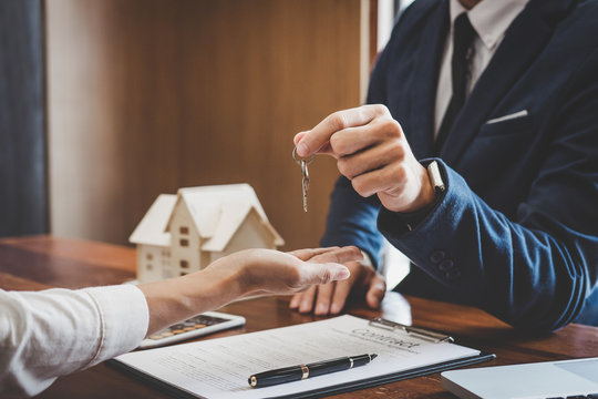 Real estate agent Sales manager holding filing keys to customer after signing rental lease contract of sale purchase agreement, concerning mortgage loan offer for and house insurance