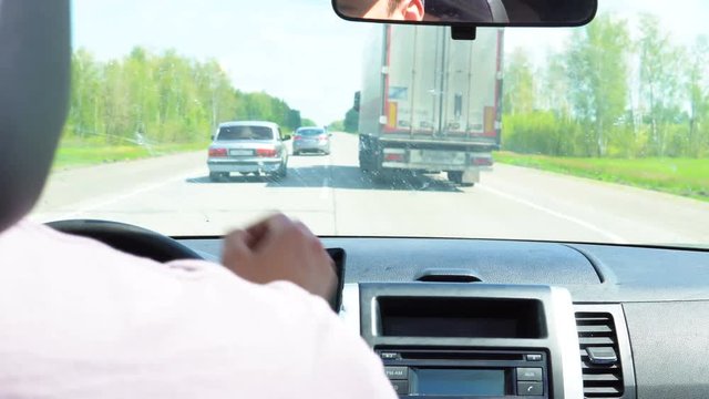 Cars overtake a truck on the road passing through the forest.