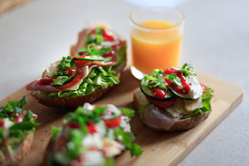 Delicious and healthy sandwiches with vegetables: lettuce, tomato, cucumber and fresh orange juice.
