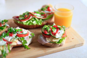 Fototapeta na wymiar Delicious and healthy sandwiches with vegetables: lettuce, tomato, cucumber and fresh orange juice.