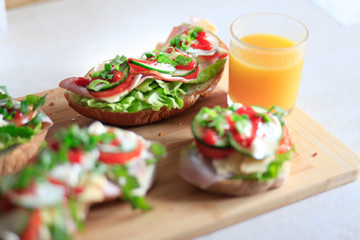 Delicious and healthy sandwiches with vegetables: lettuce, tomato, cucumber and fresh orange juice.