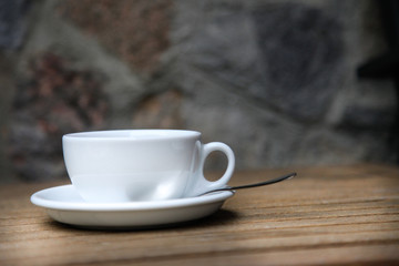White cup with brown coffee on a wooden table.