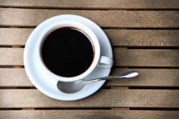 White cup with brown coffee on a wooden table.