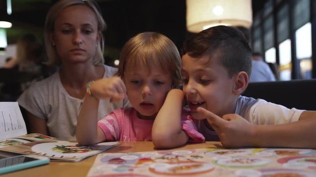 mom with children chooses pizza in a cafe and have a fun