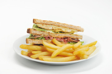 Fried french fries on a white plate. Next to the potato is a half-club sandwich with chicken meat and bacon. White background. Close-up. Macro photography.