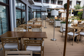 empty resort hotel yard patio cafe with wooden white furniture chairs armchairs tables and umbrellas 