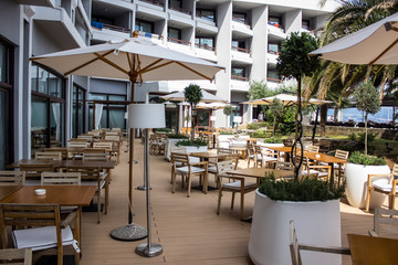 empty resort hotel yard patio cafe with wooden white furniture chairs armchairs tables and umbrellas 