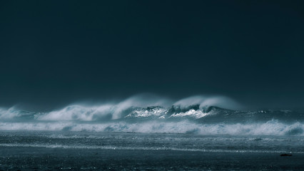 Large barrel wave creating a mist of glassy water as it rushes towards island. © helivideo