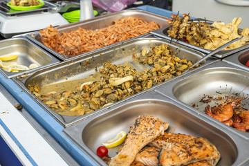 table with seafood cooked on the grill, fried fish, shrimp and mussels on the counter