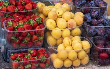 strawberries with apricots and plums in the plastic in the store, seasonal fruits
