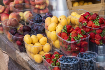 fresh fruit in the store, strawberries with apricots and plums in the plastic in the store, seasonal fruits