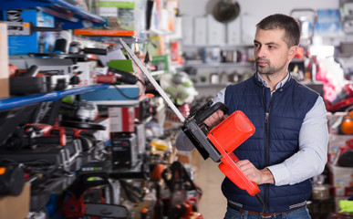 Cheerful man is buying new electric saw