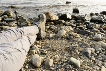 The traveler sat down on a rocky beach, putting his foot on his leg